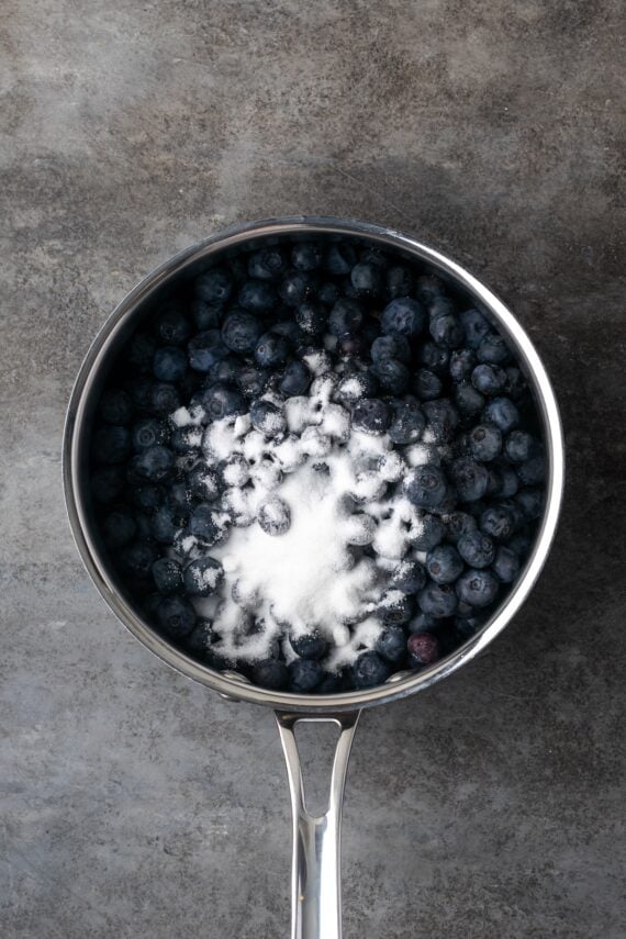 Sugar added to blueberries in a saucepan.