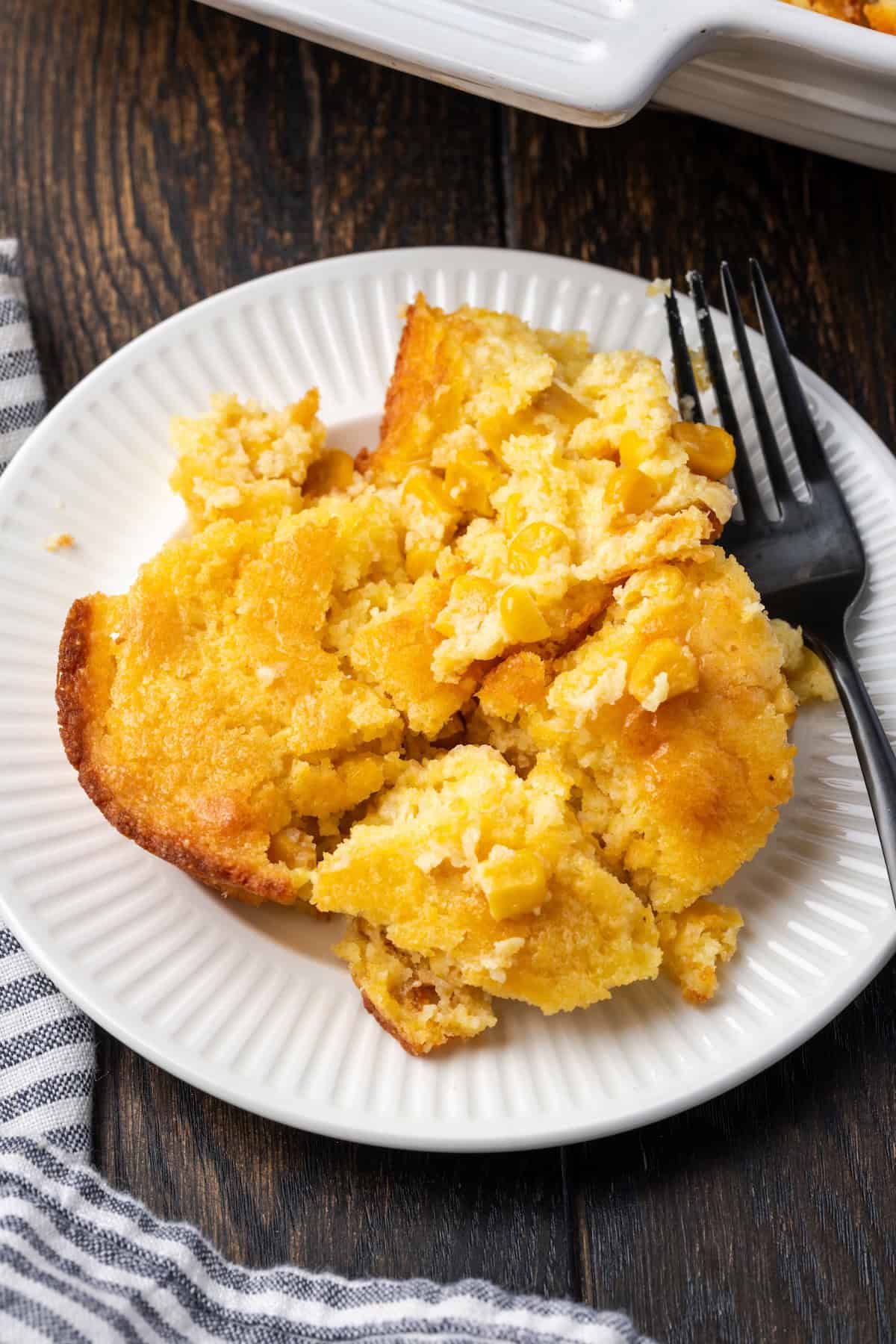 Old-fashioned spoon bread is a soft, creamy twist on cornbread that you eat with a spoon! It's a comforting Southern side dish for any meal. A serving of spoon bread on a plate with a fork.