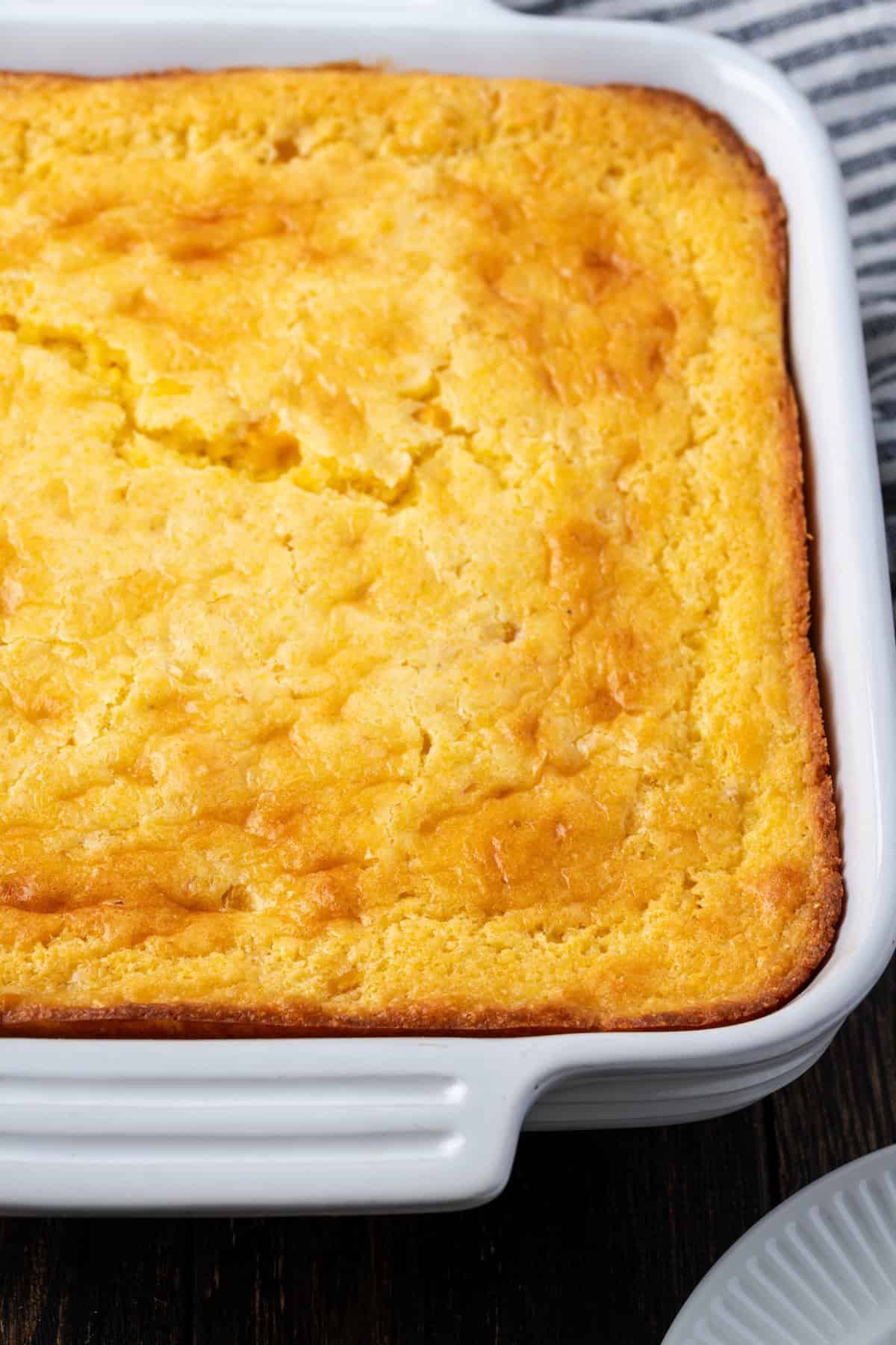 Old-fashioned spoon bread is a soft, creamy twist on cornbread that you eat with a spoon! It's a comforting Southern side dish for any meal. Overhead view of spoon bread in a ceramic baking dish.