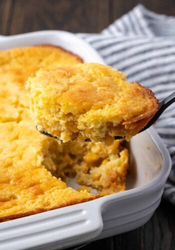 Spoon bread in a baking dish with a spoon scooping from the corner.