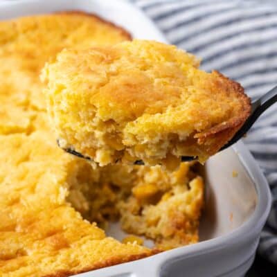 Spoon bread in a baking dish with a spoon scooping from the corner.