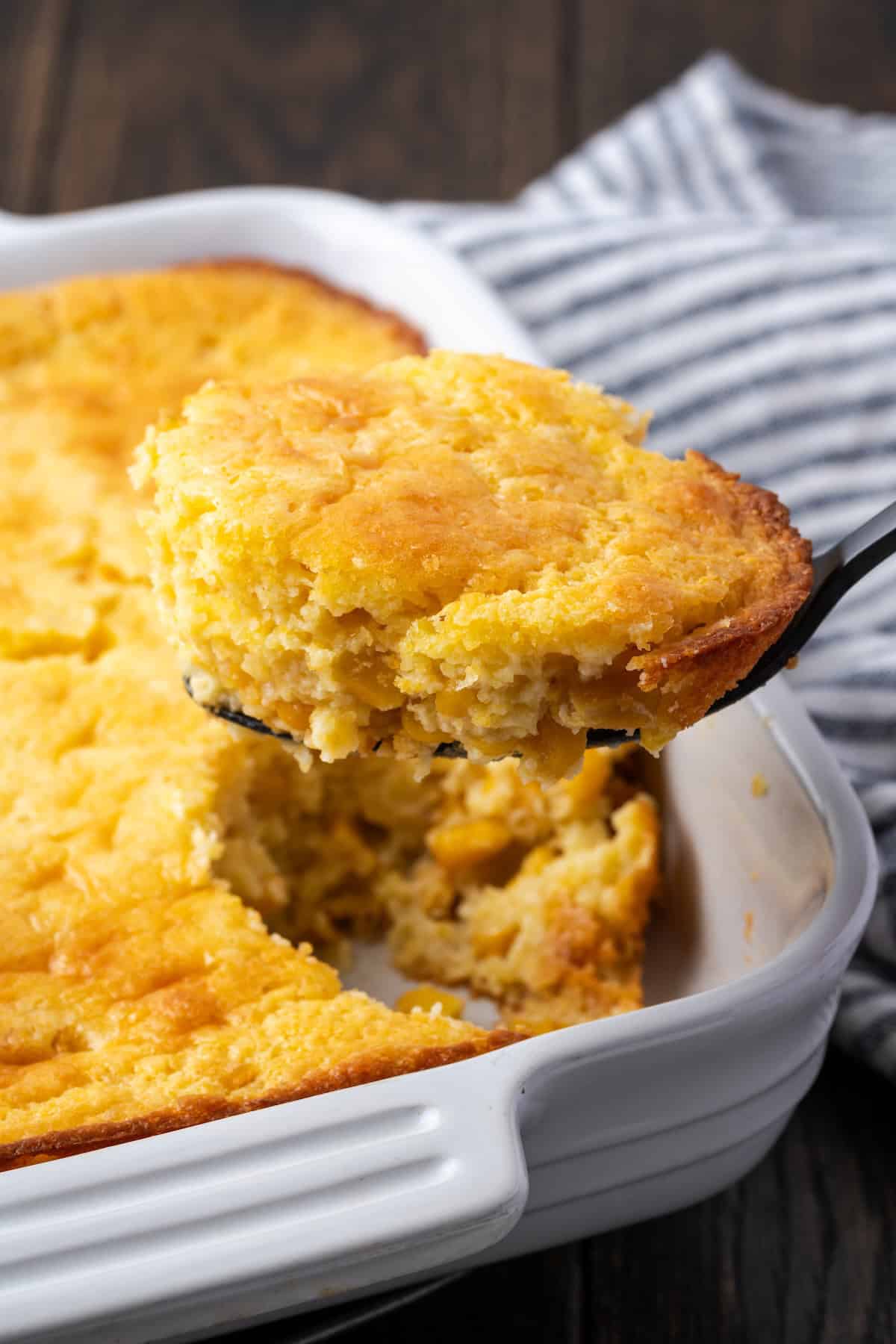 Old-fashioned spoon bread is a soft, creamy twist on cornbread that you eat with a spoon! It's a comforting Southern side dish for any meal. Spoon bread in a baking dish with a spoon scooping from the corner.