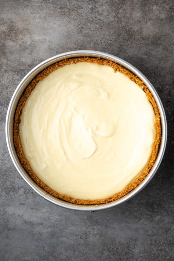 This homemade apple cheesecake recipe has a buttery graham cracker crust layered with creamy cheesecake and a gooey caramel apple topping. Graham cracker crust filled with cheesecake batter inside a springform pan.