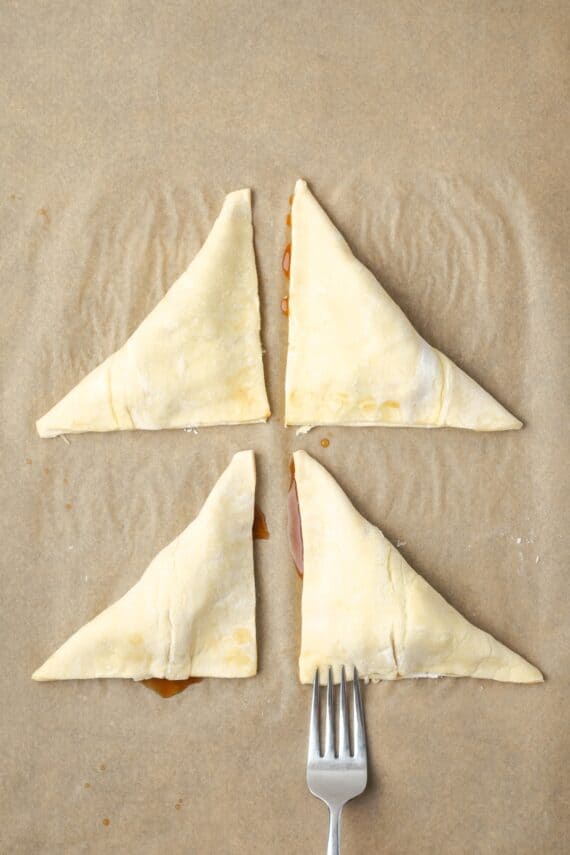 Crispy, buttery store-bought puff pastry and quick, homemade apple filling make these easy apple turnovers the perfect fall weekend treat! A fork being used to seal the edges of the pastry dough around the apple filling.