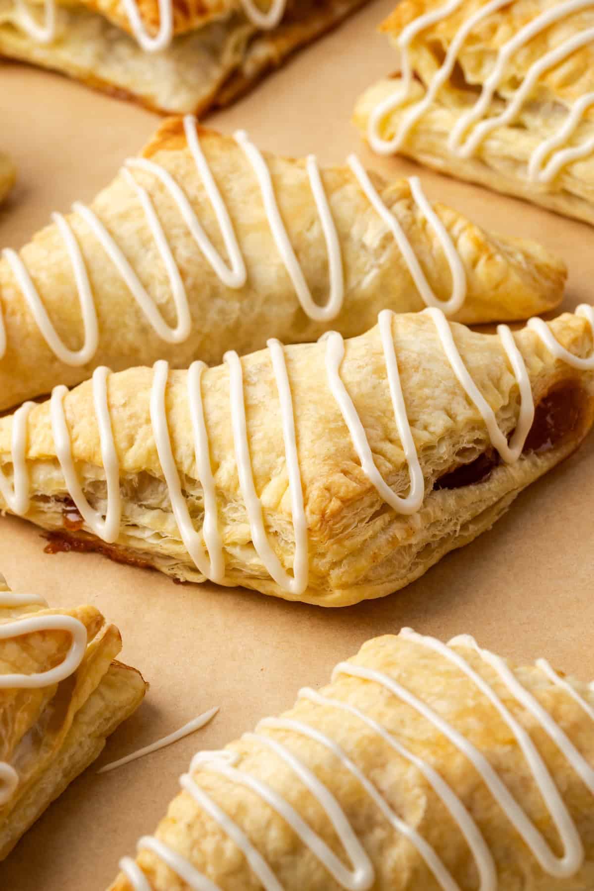 Crispy, buttery store-bought puff pastry and quick, homemade apple filling make these easy apple turnovers the perfect fall weekend treat! Apple turnovers drizzled with icing on a baking sheet.