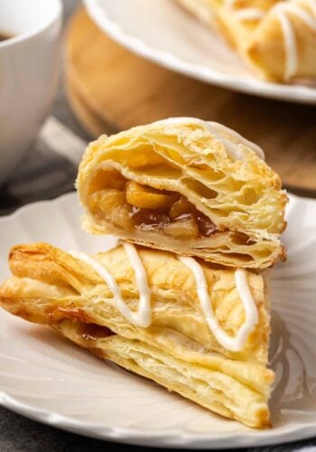Two halves of an apple turnover stacked on a plate.