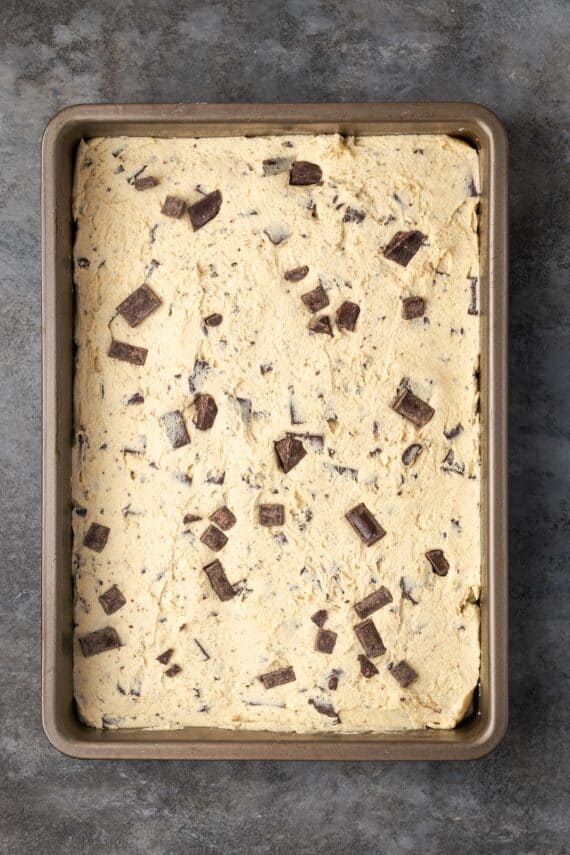 Chocolate chip cookie dough pressed into a rectangular baking pan.