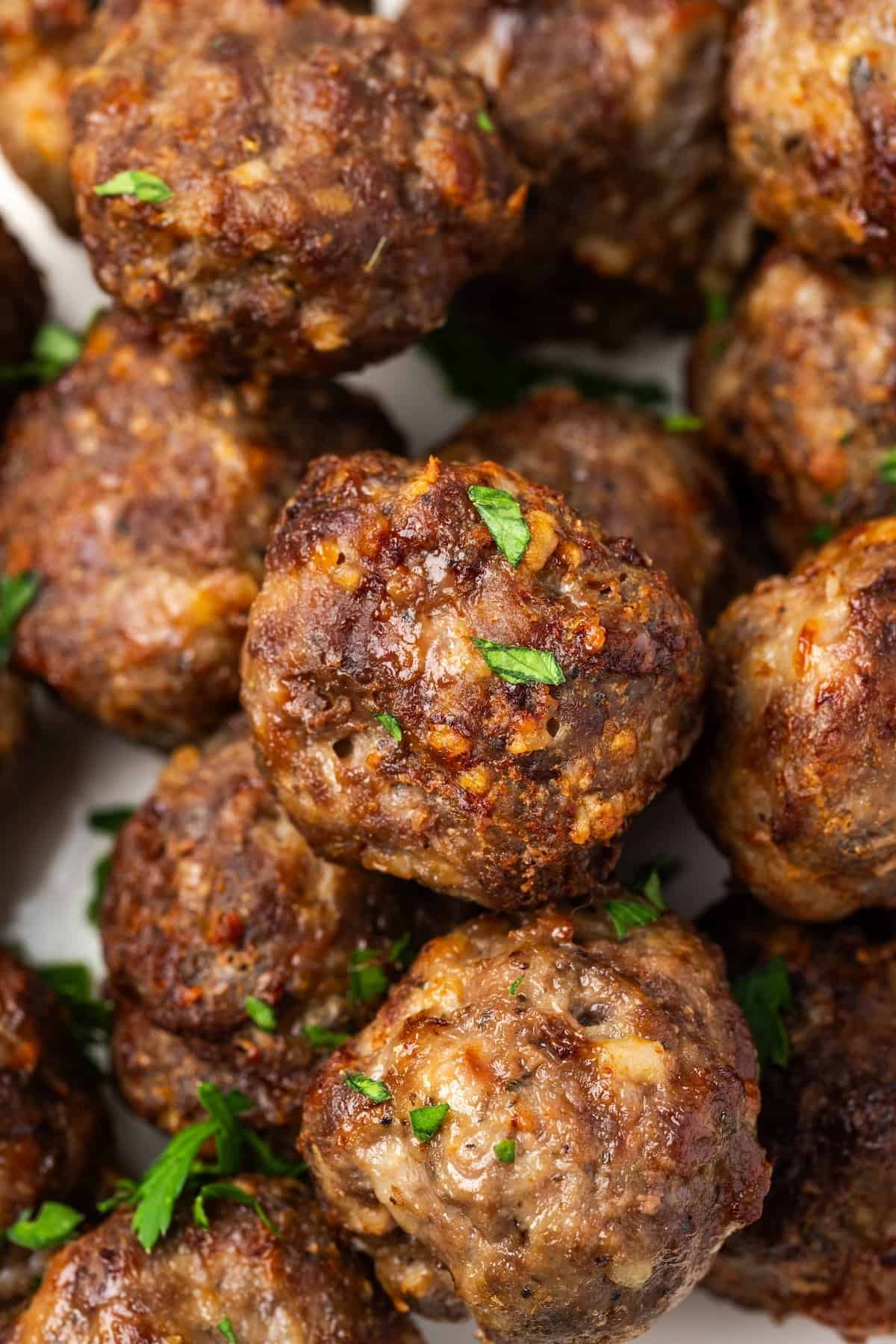 Close up of air fryer meatballs piled on a white serving platter.