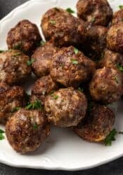 Air fryer meatballs piled on a white serving platter.