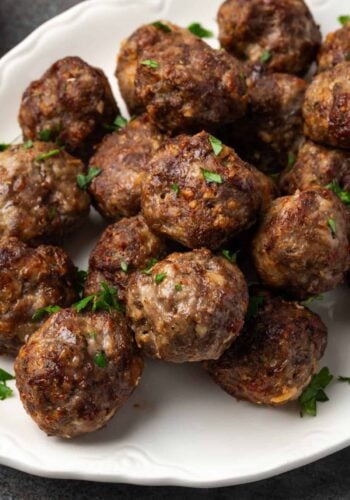 Air fryer meatballs piled on a white serving platter.