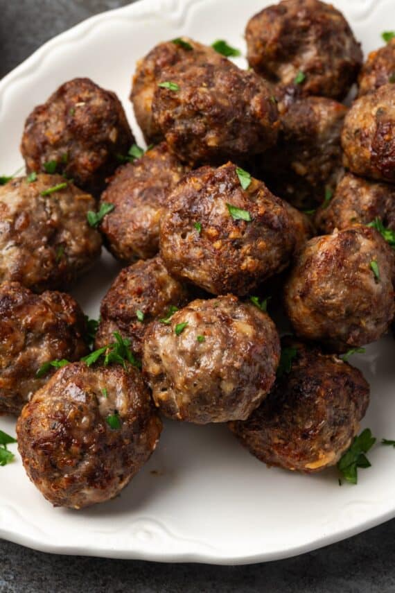 Air fryer meatballs piled on a white serving platter.
