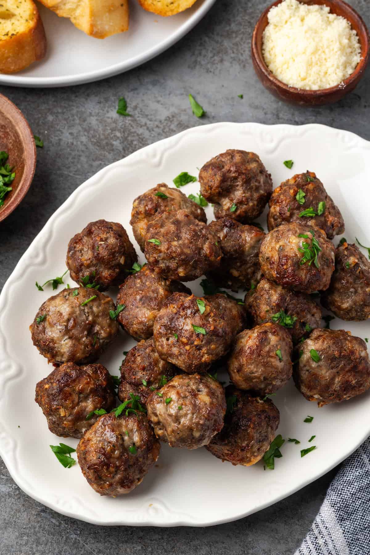 Overhead view of air fryer meatballs piled on a white serving platter.