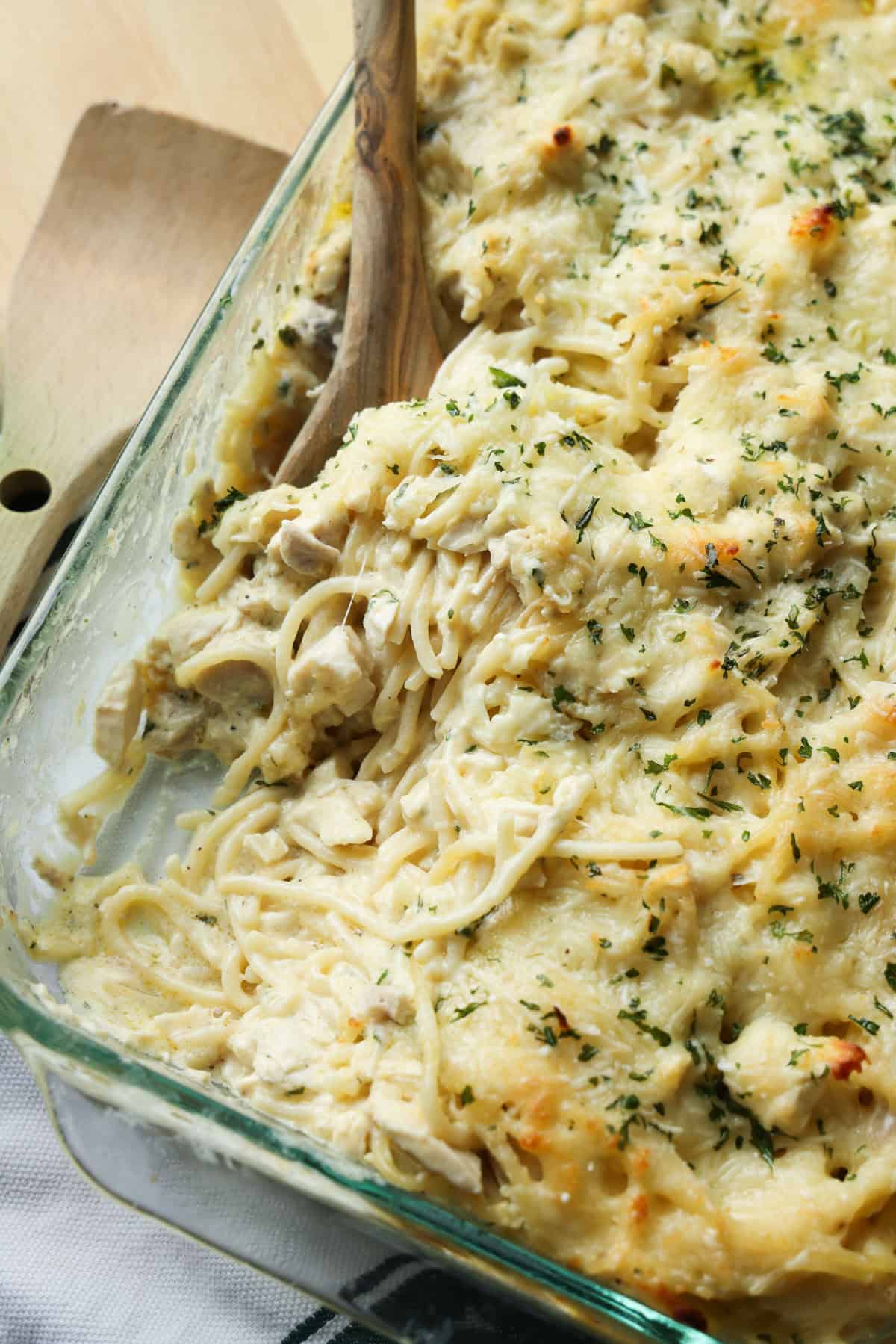 Creamy chicken tetrazzini is an easy pasta bake that's ready in under an hour! Made with juicy chicken and spaghetti in a rich cream sauce. Close up of creamy chicken tetrazzini in a glass casserole dish with a portion missing.