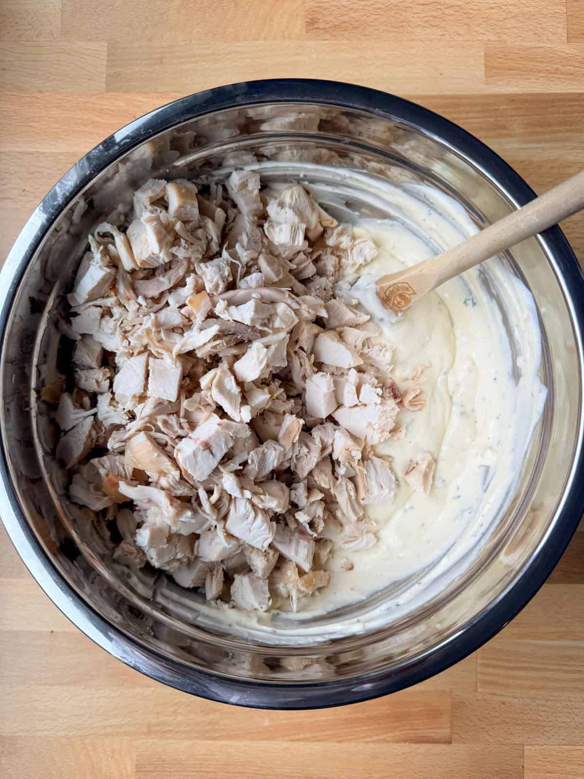 Creamy chicken tetrazzini is an easy pasta bake that's ready in under an hour! Made with juicy chicken and spaghetti in a rich cream sauce. Chicken added to the cream sauce for tetrazzini in a metal bowl.