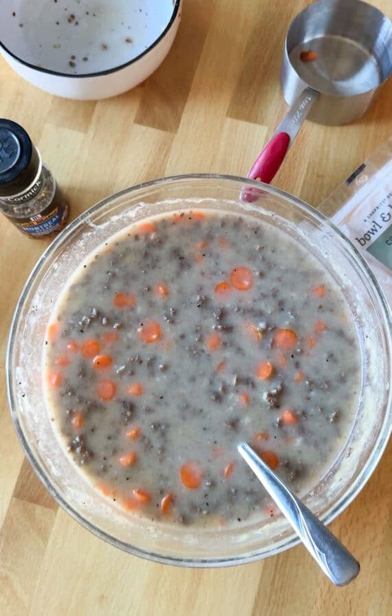 Mixture of beef casserole ingredients in a glass bowl shown from above
