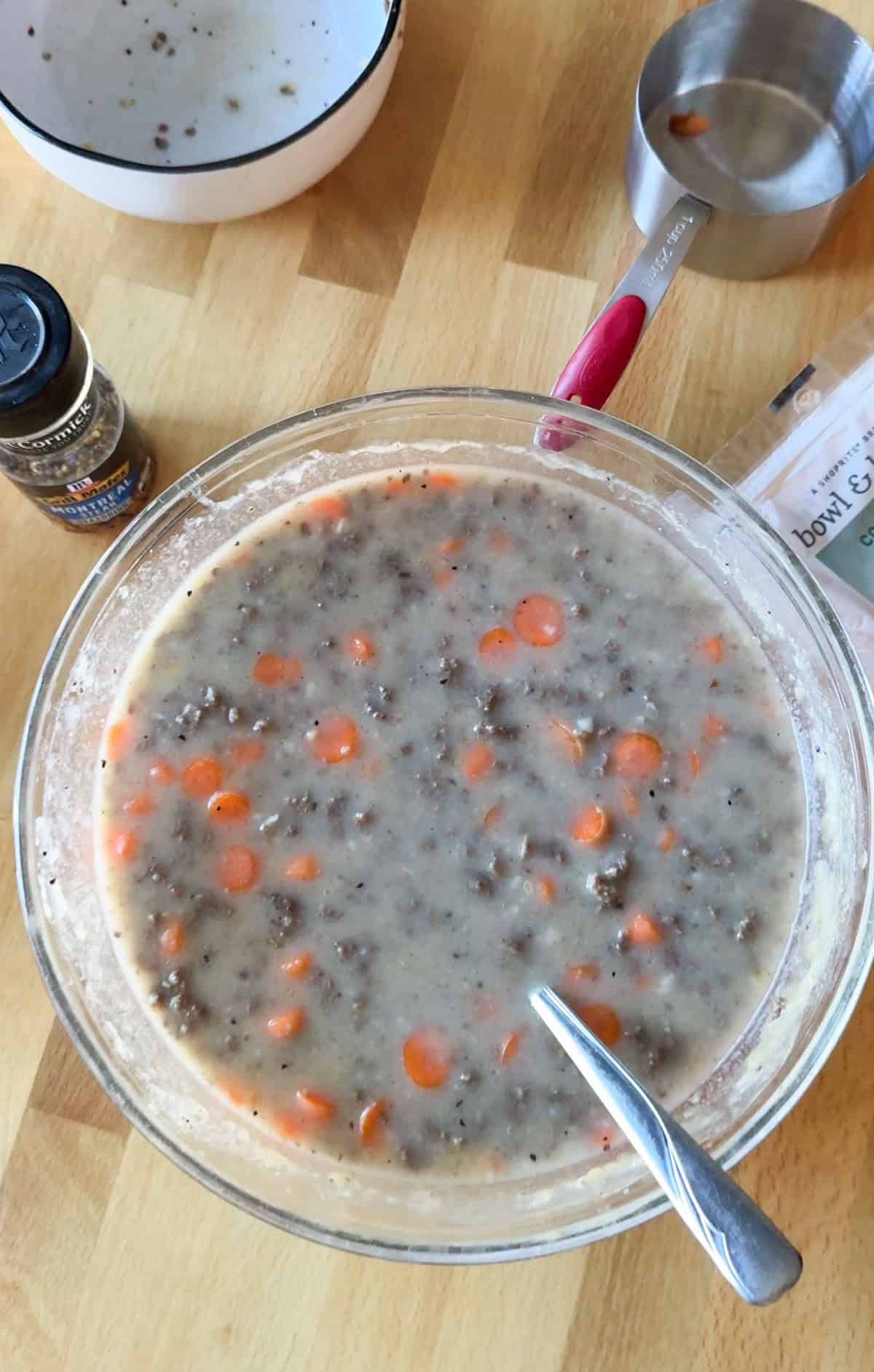 Mixture of beef casserole ingredients in a glass bowl shown from above