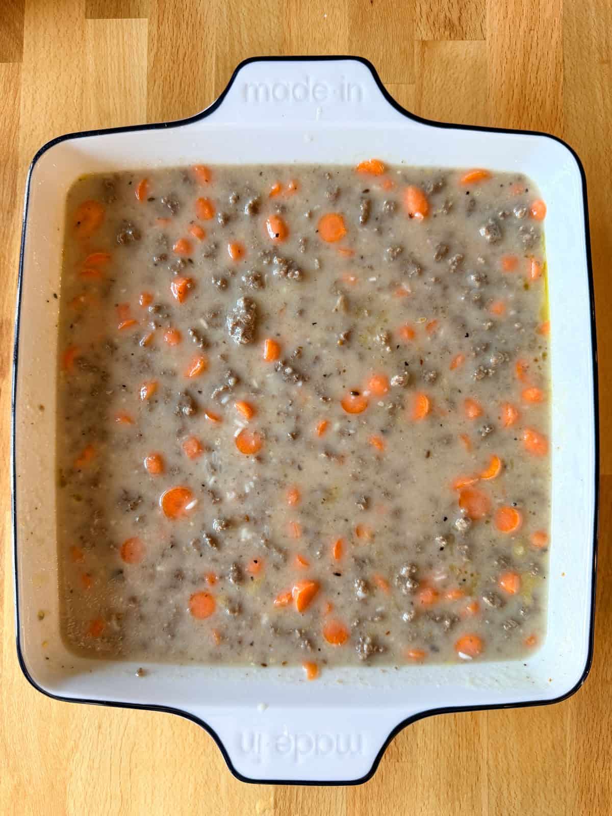 Ground beef casserole ingredients in a 9x9 baking dish before going in the oven.