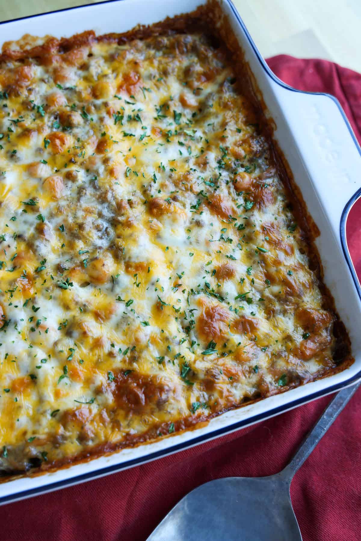 Cheese topped ground beef casserole right out of the oven baked in a white casserole dish from above.
