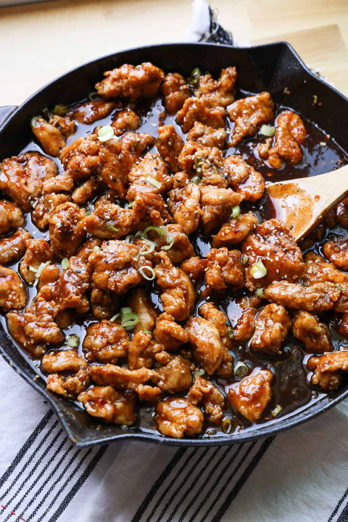 This copycat PF Chang’s spicy chicken recipe is a quick and delicious sweet and spicy stir-fry! Make it in one skillet and serve it with rice. Copycat PF Chang's spicy chicken in a skillet with a wooden spoon.