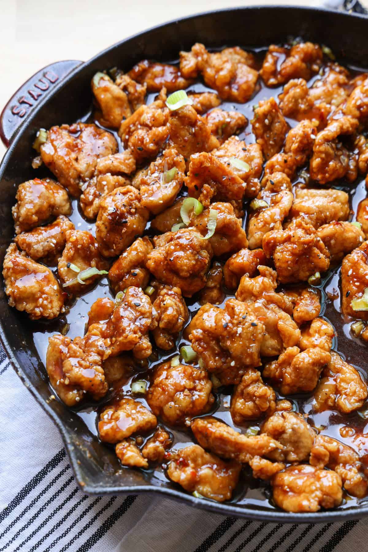 This copycat PF Chang’s spicy chicken recipe is a quick and delicious sweet and spicy stir-fry! Make it in one skillet and serve it with rice. Close up of copycat PF Chang's spicy chicken in a skillet with a wooden spoon.