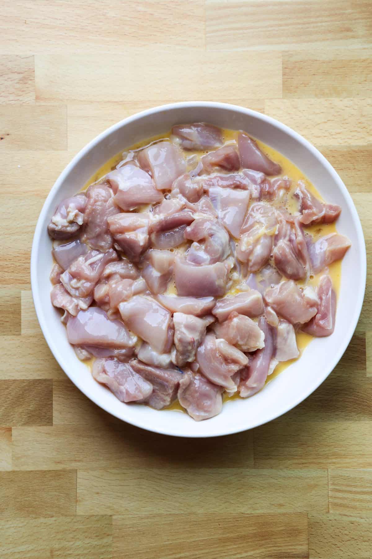 This copycat PF Chang’s spicy chicken recipe is a quick and delicious sweet and spicy stir-fry! Make it in one skillet and serve it with rice. Chicken pieces added to beaten eggs in a bowl