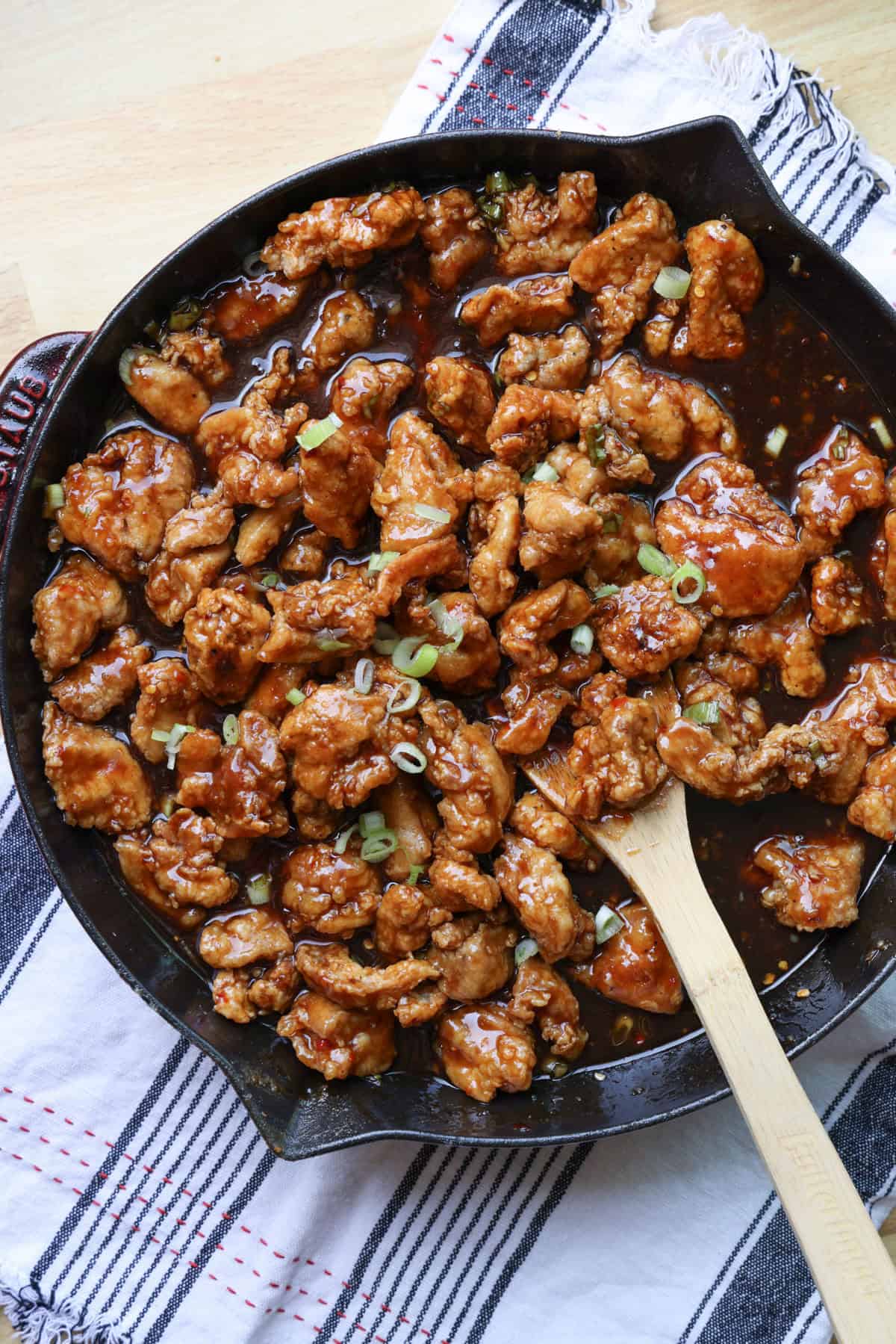 This copycat PF Chang’s spicy chicken recipe is a quick and delicious sweet and spicy stir-fry! Make it in one skillet and serve it with rice. Overhead view of copycat PF Chang's spicy chicken in a skillet with a wooden spoon.