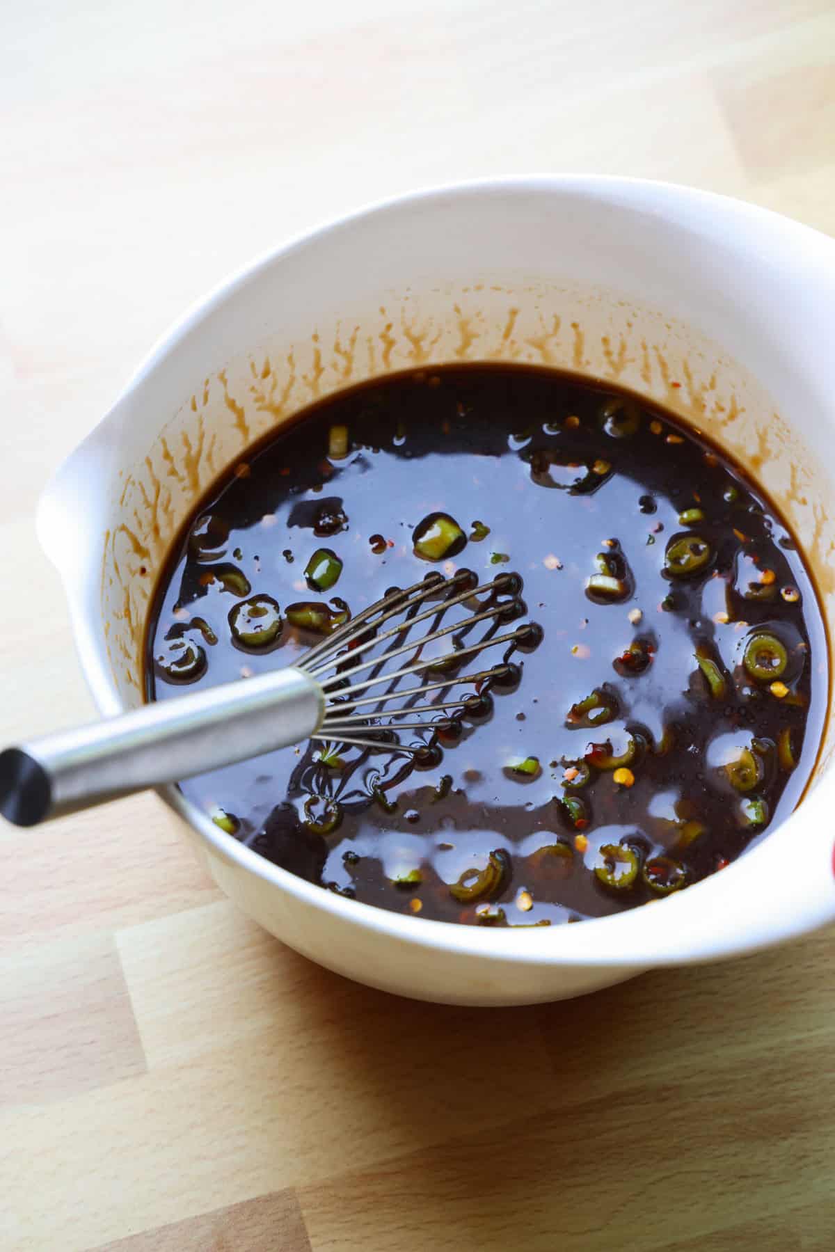 This copycat PF Chang’s spicy chicken recipe is a quick and delicious sweet and spicy stir-fry! Make it in one skillet and serve it with rice. PF Chang's spicy chicken stir-fry sauce in a bowl with a whisk.