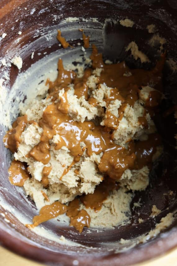 Cookie dough with melted Biscoff spread drizzled on top in a mixing bowl.