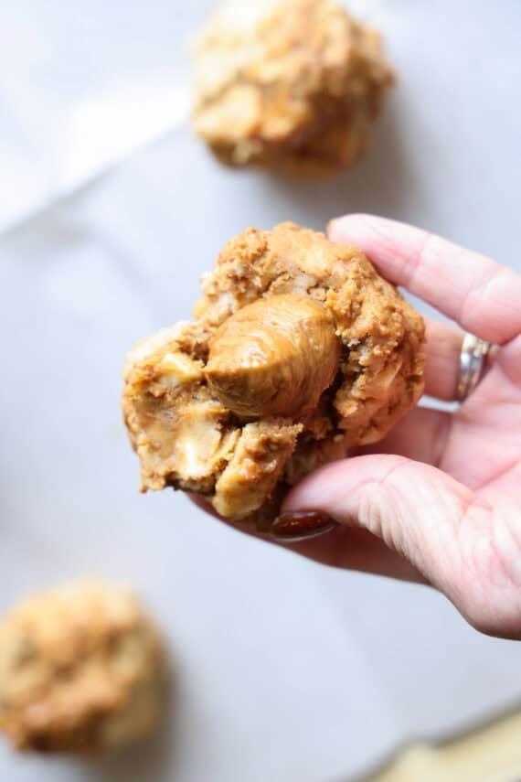 A swirl of Biscoff spread being stuffed into raw cookie dough before being baked being held by a hand.