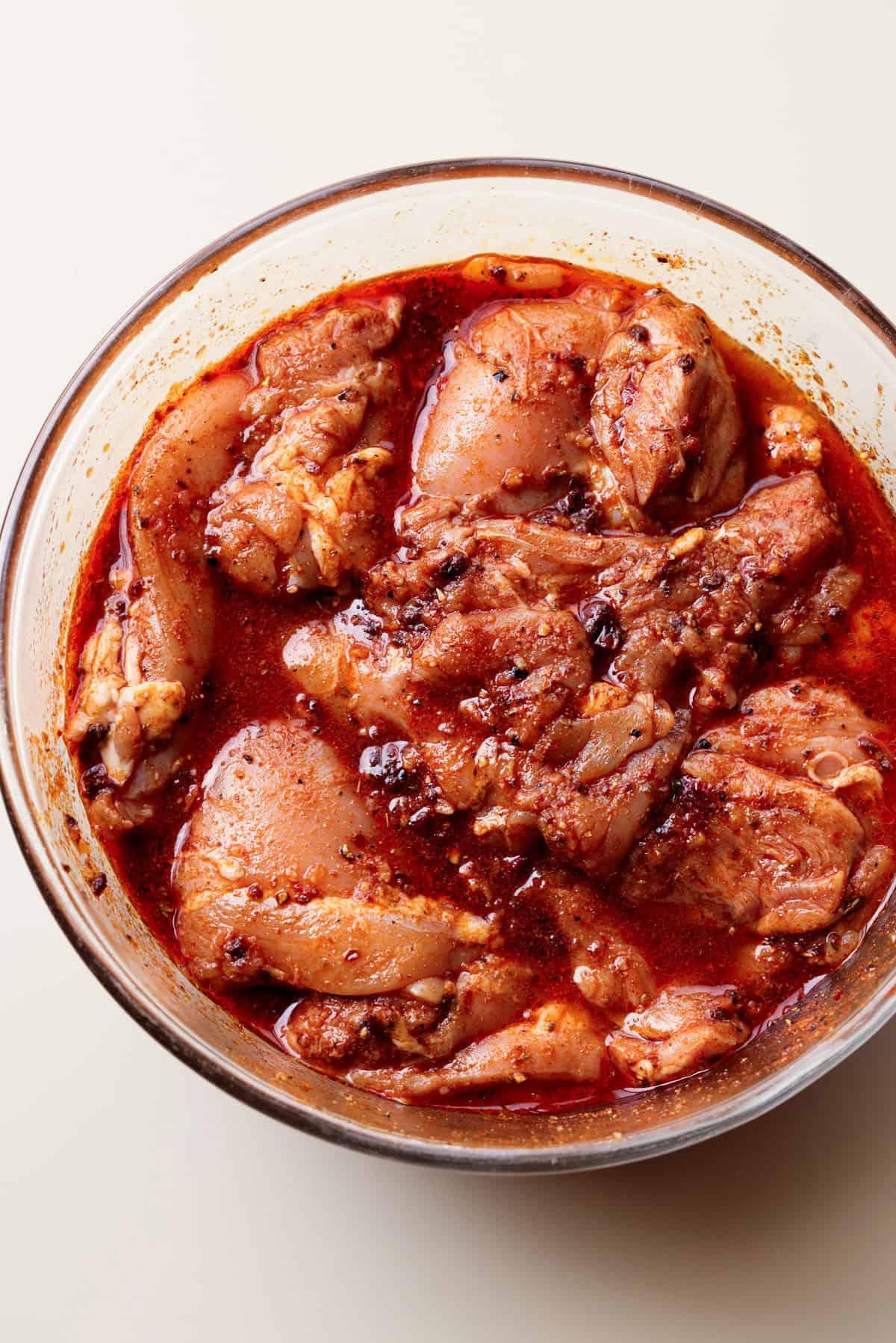 Chicken thighs soaked in a bowl of Chipotle marinade.