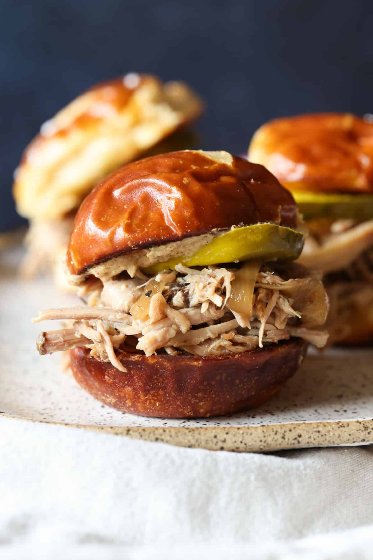 This crock pot pulled pork recipe makes the best sliders! Juicy pork shoulder is slow-cooked with apple marinade until it's fall-apart-tender. Crock pot pulled pork sliders assembled in fluffy buns with BBQ sauce.