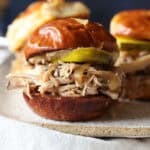 Crock pot pulled pork sliders assembled in fluffy buns with BBQ sauce.