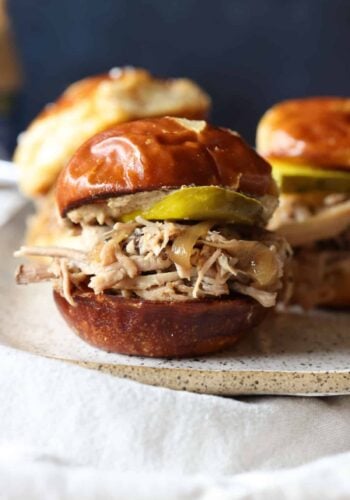 Crock pot pulled pork sliders assembled in fluffy buns with BBQ sauce.