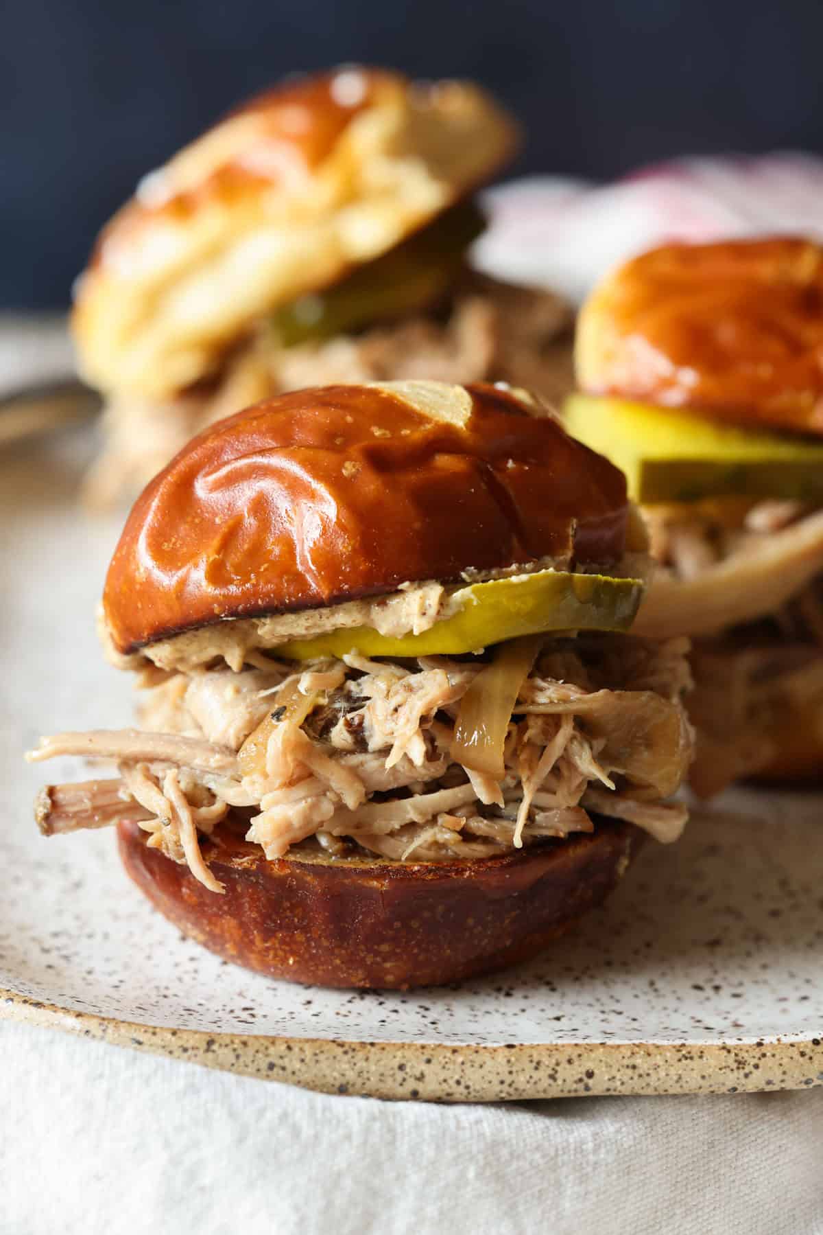 This crock pot pulled pork recipe makes the best sliders! Juicy pork shoulder is slow-cooked with apple marinade until it's fall-apart-tender. Crock pot pulled pork sliders assembled in fluffy buns with BBQ sauce.