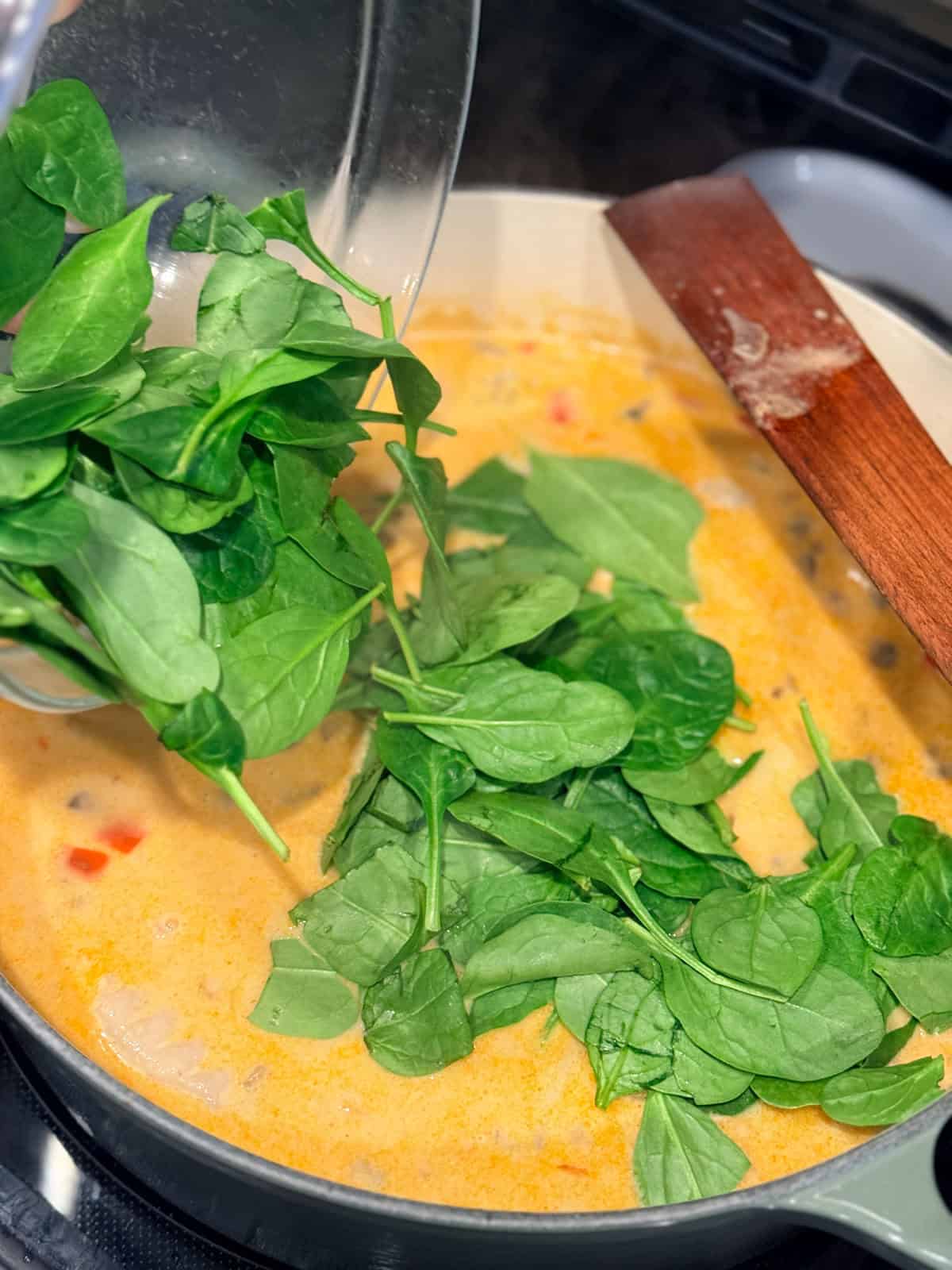 This coconut curry soup has tender Chinese potstickers swimming in a rich coconut broth with veggies. Ready in one pot in under an hour! Spinach added to a pot of coconut curry potsticker soup.