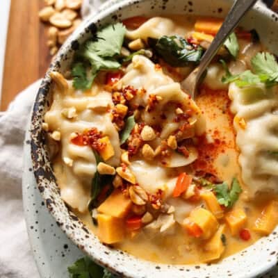 Overhead view of coconut curry potsticker soup in a bowl with a spoon.