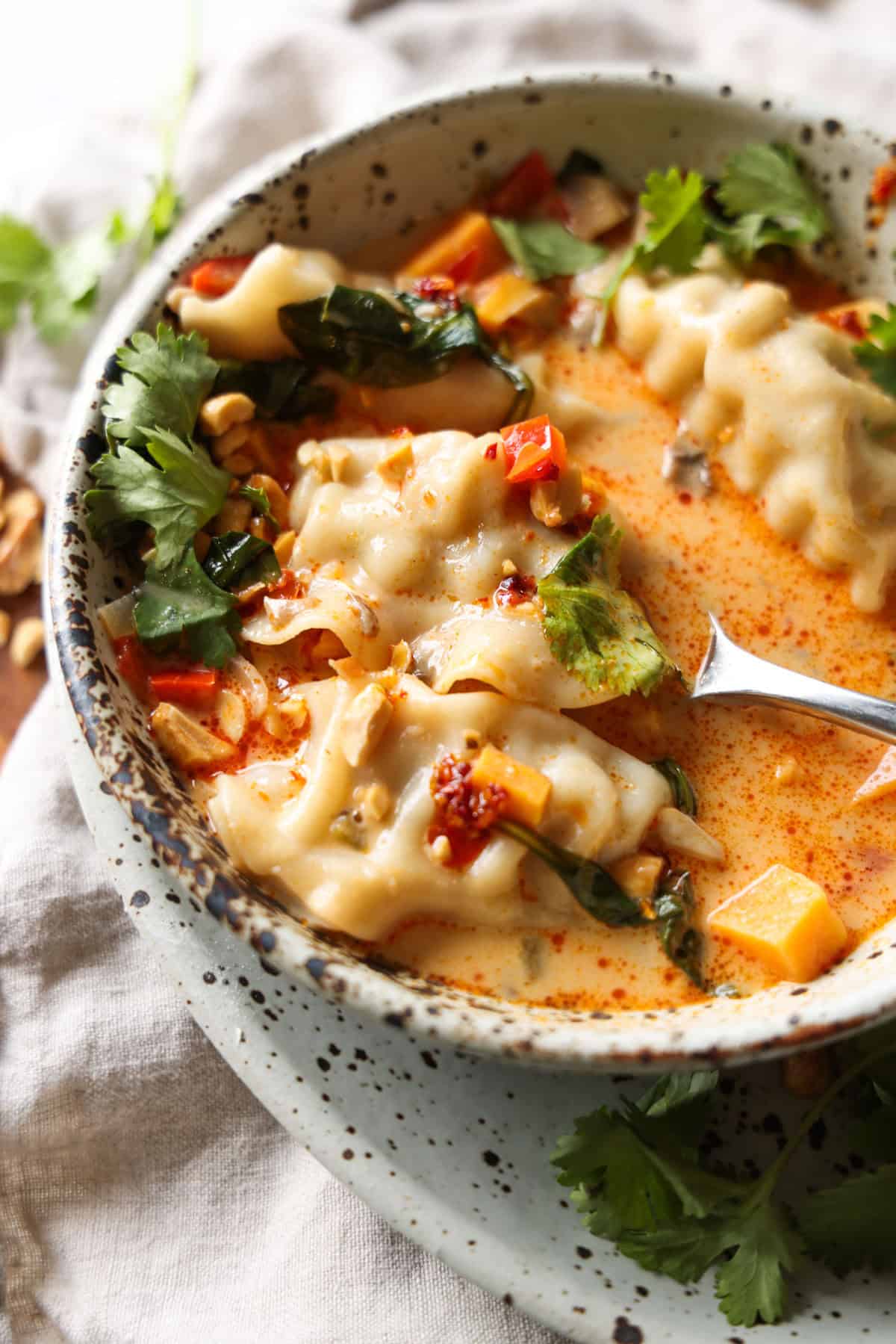This coconut curry soup has tender Chinese potstickers swimming in a rich coconut broth with veggies. Ready in one pot in under an hour! Overhead view of coconut curry potsticker soup in a bowl with a spoon.