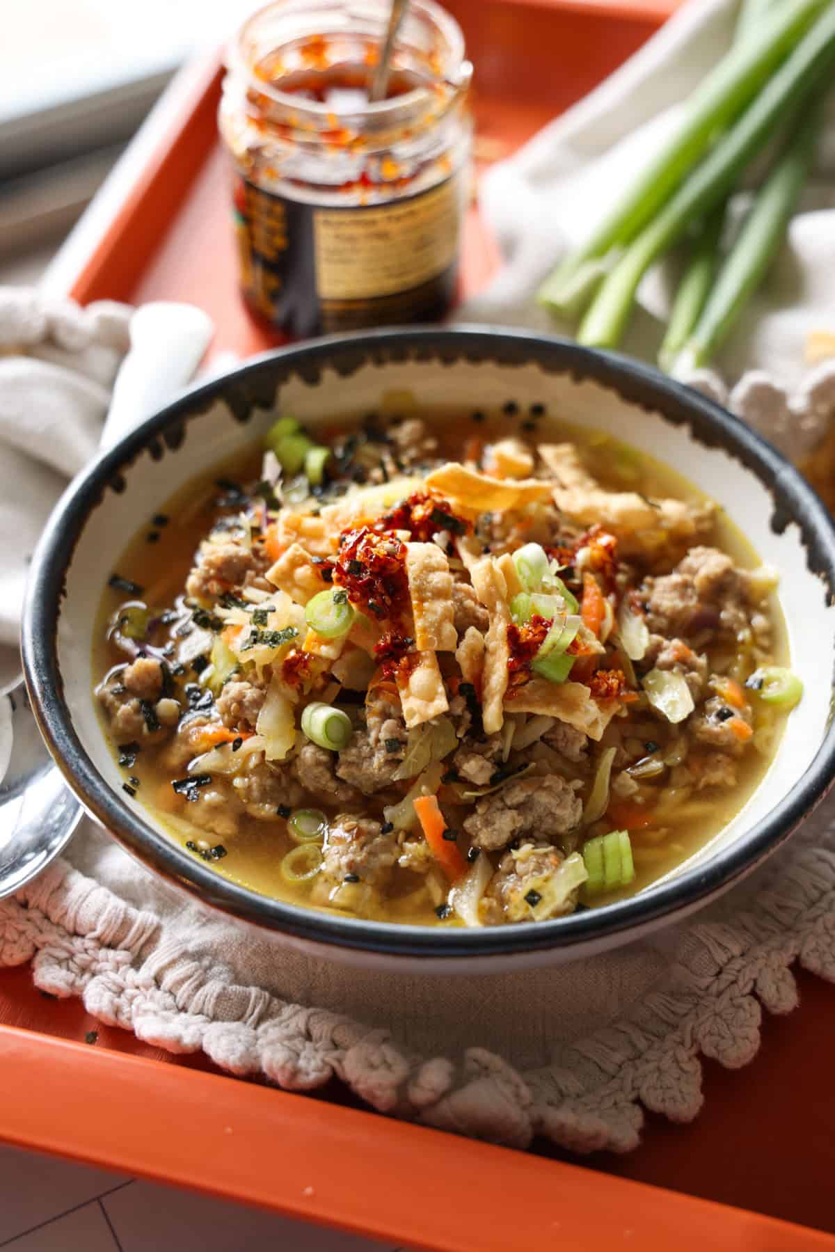 This easy egg roll soup has all the Asian-inspired flavors you love, with juicy ground pork simmered with tender cabbage, sesame, and ginger. A bowl of egg roll soup garnished with green onions and crispy wonton strips.