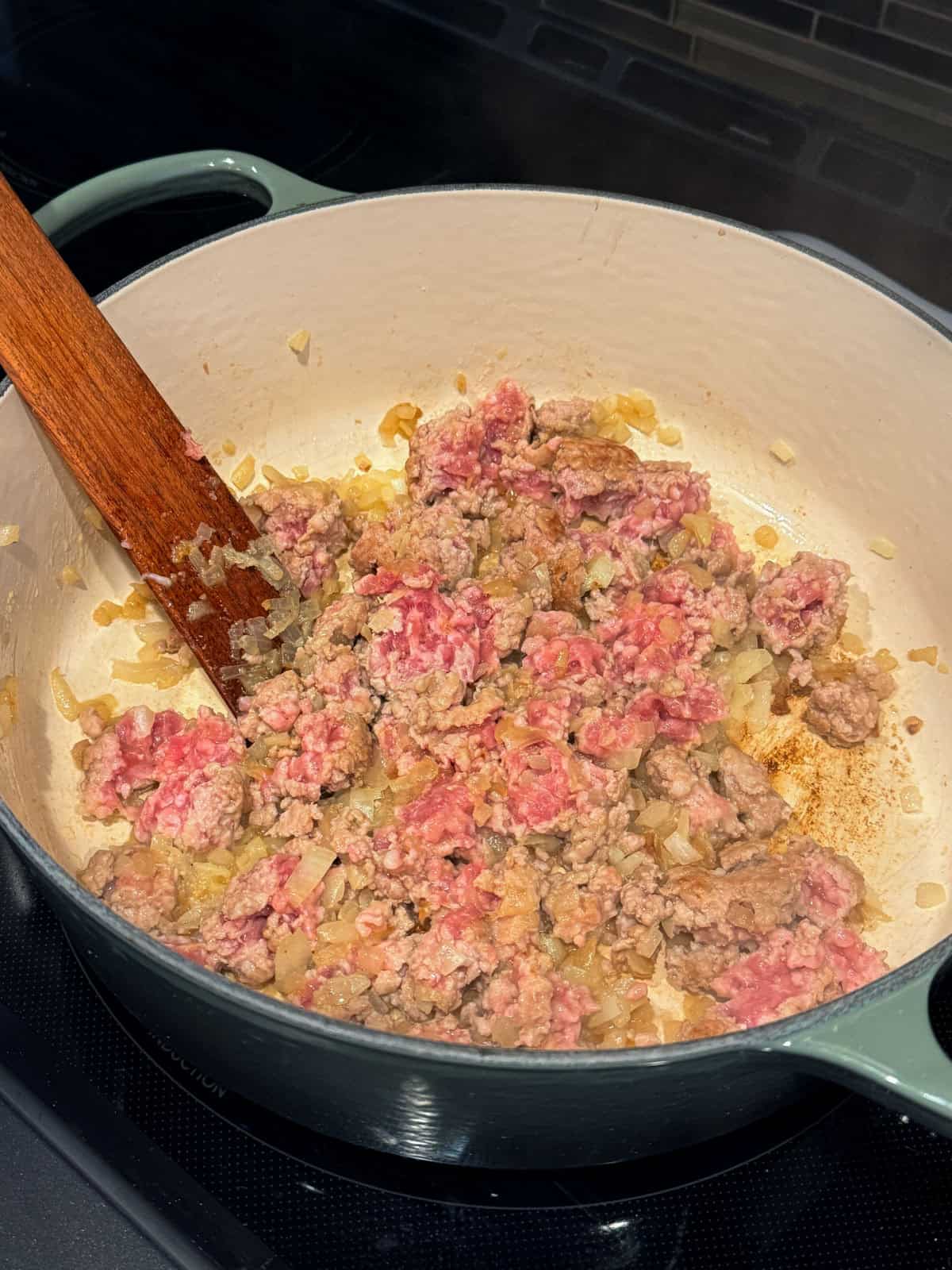 This easy egg roll soup has all the Asian-inspired flavors you love, with juicy ground pork simmered with tender cabbage, sesame, and ginger. Ground pork browning in a Dutch oven.
