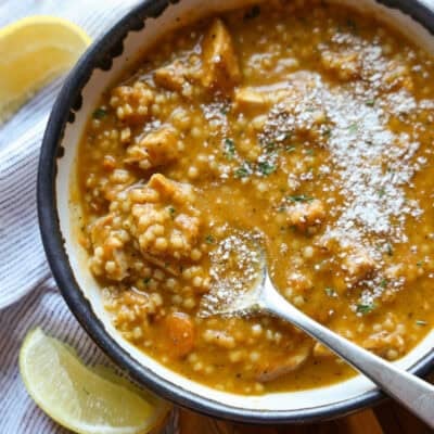 A bowl of creamy Italian Pastina Soup shot from above with parmesan cheese on top and a spoon