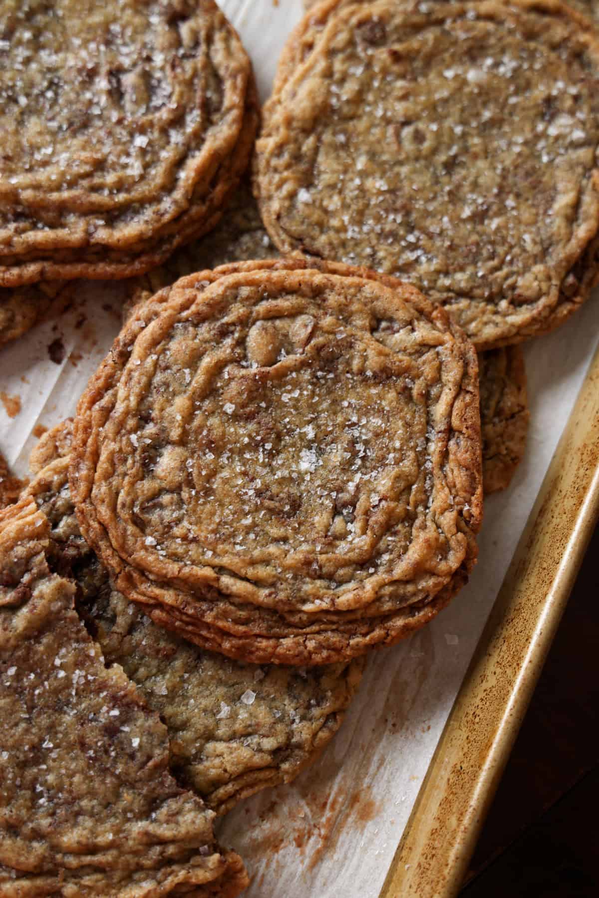 Giant Crinkled Chocolate Chip Cookies stacked on a parchment lined baking sheet from above