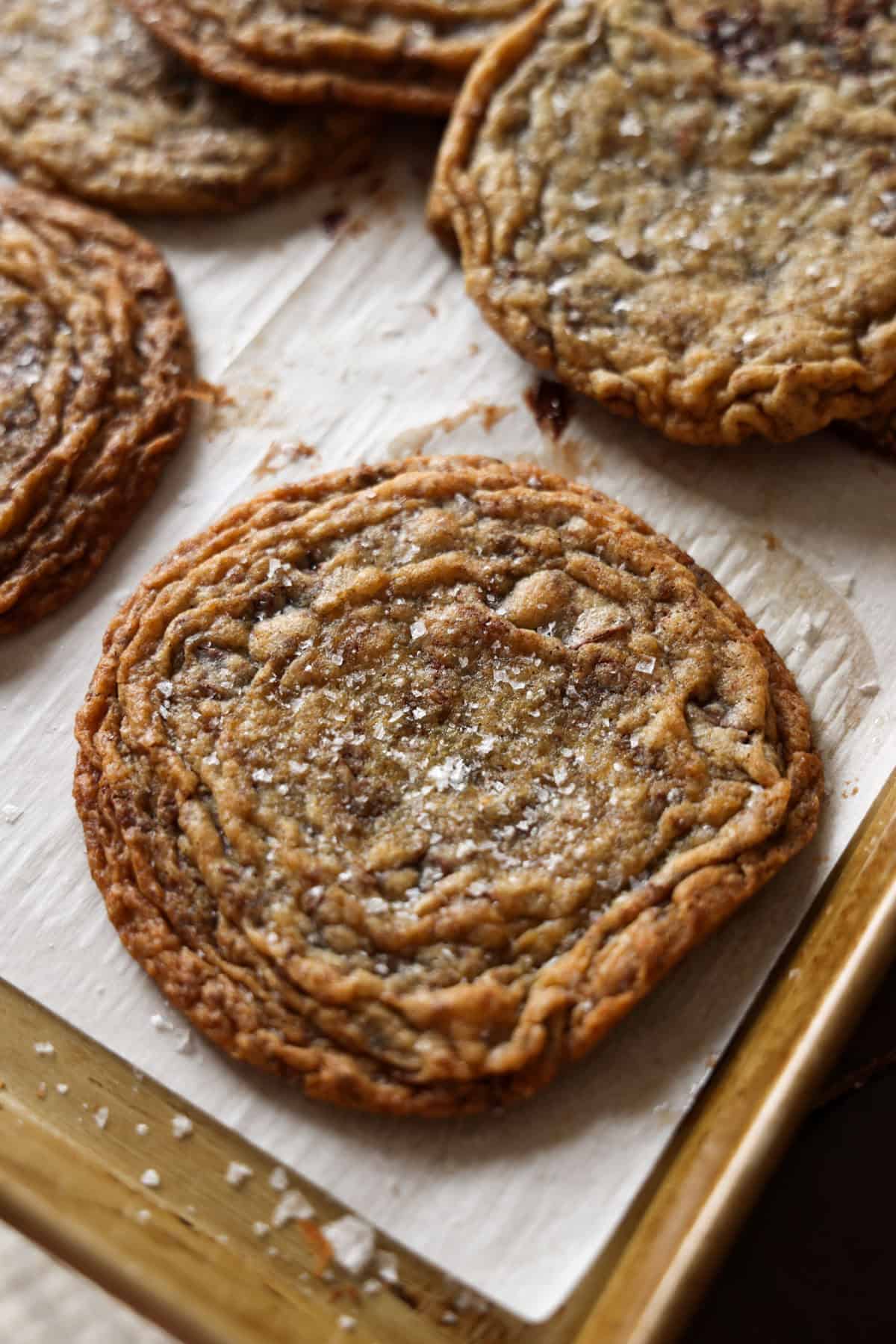 Giant Pan-Banged Crinkled Chocolate Chip Cookies on a parchment lined baking sheet