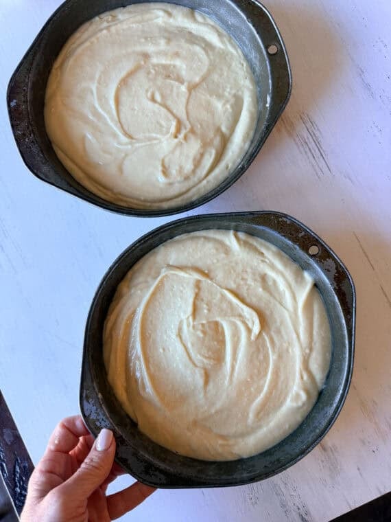 Once the cakes have baked, cool them and then level them off if domes have formed (if necessary). Use a serrated knife to slice the cakes in half. Cake batter divided between two 8- inch round cake pans