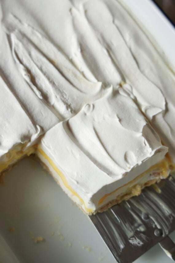 Serving a slice of Lemon Lush dessert out of a 9x13 pan with a spatula.