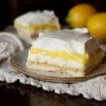 A slice of lemon pudding lush on a plate with whipped cream topping.