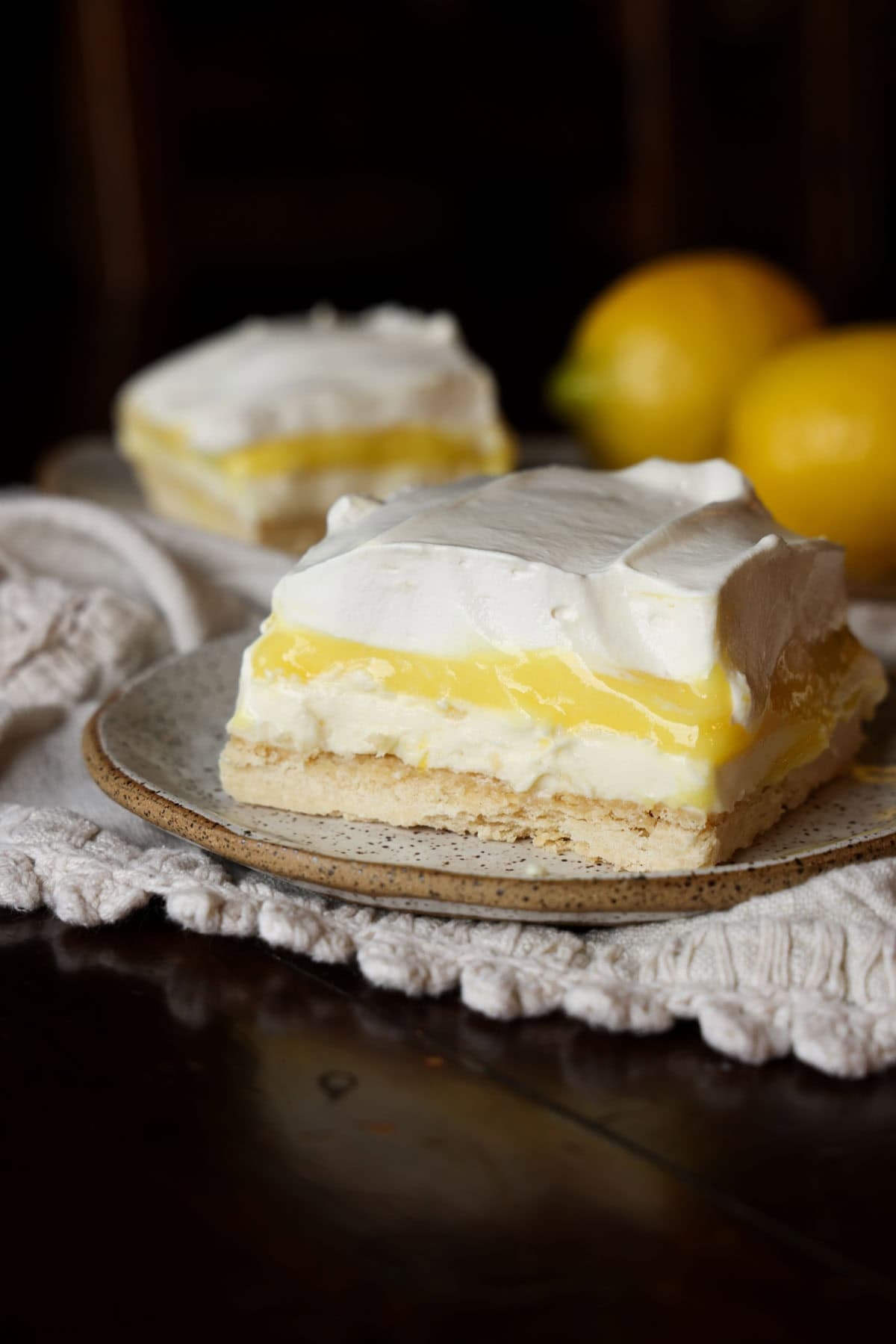 A slice of lemon pudding lush on a plate with whipped cream topping.