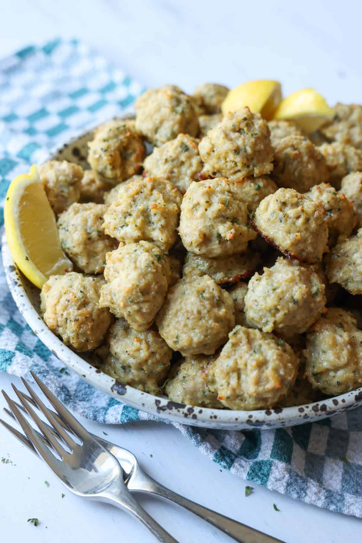 Chicken meatballs in a ceramic bowl with lemon wedges