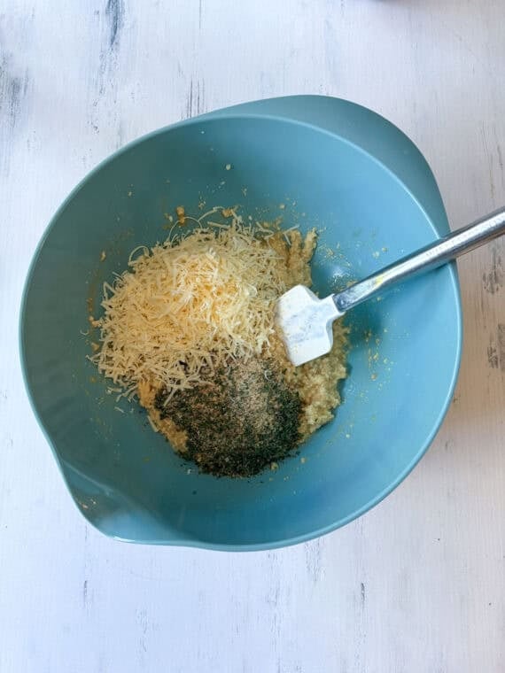 Parmesan cheese, seasonings, breadcrumbs in a bowl being mixed.