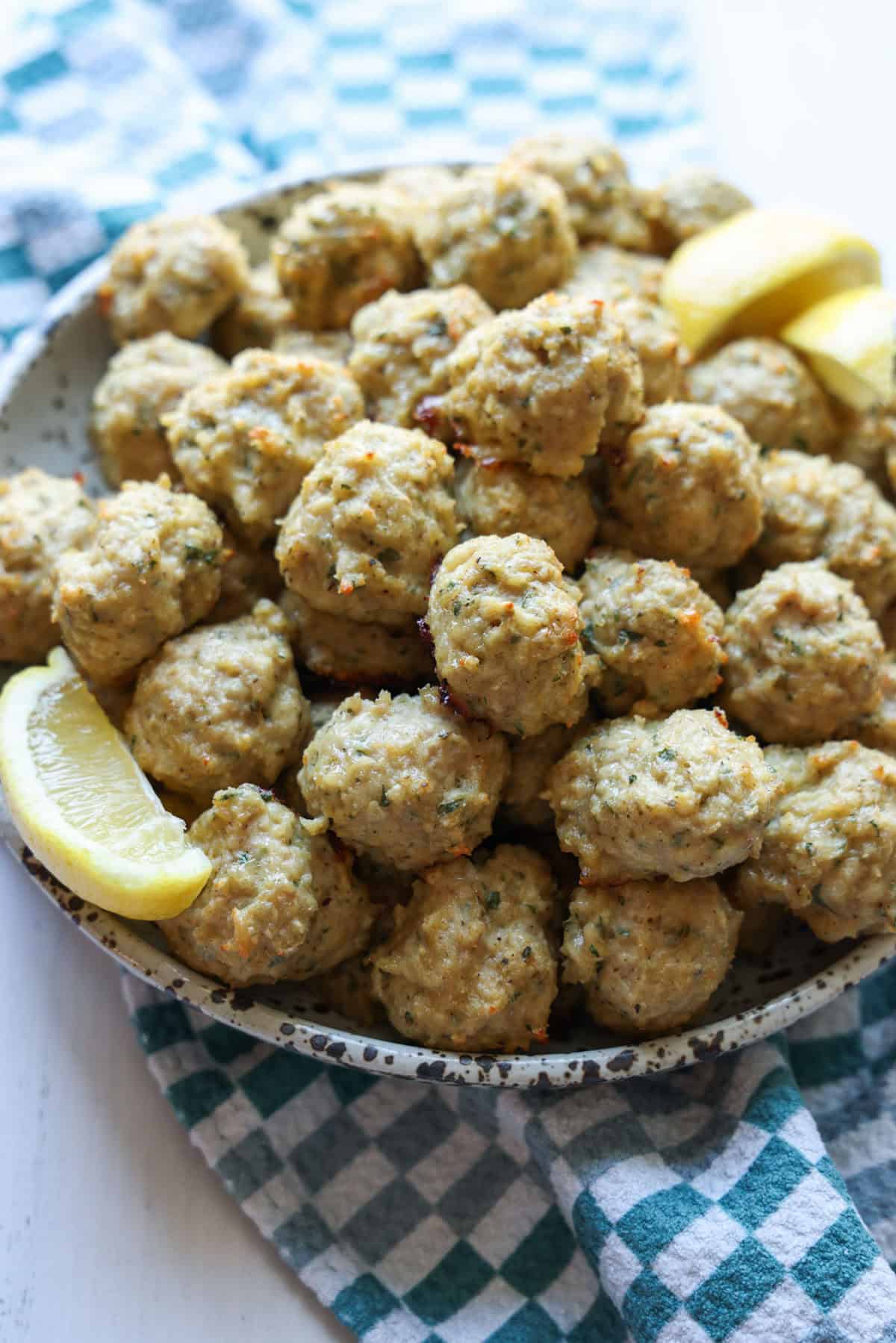 Chicken Meatballs in a bowl garnished with lemon slices