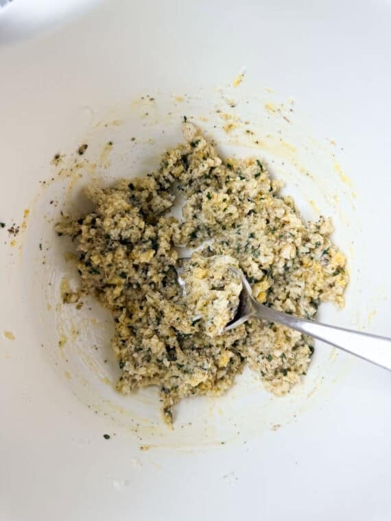 Soaked breadcrumbs and seasonings in a white mixing bowl.